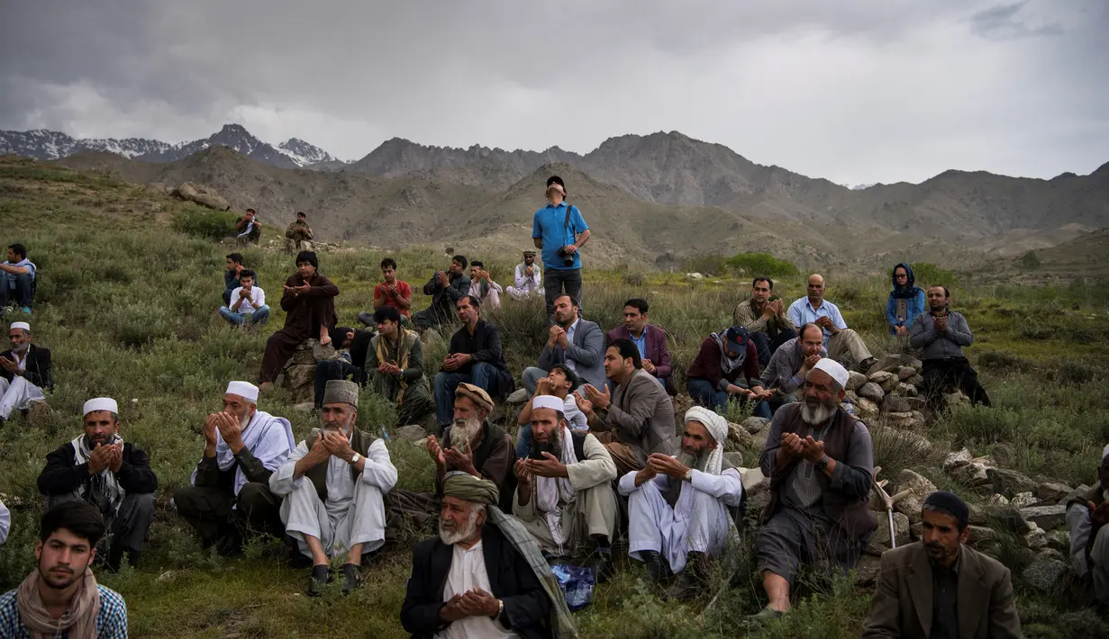 Teman dan kerabat berdoa di pemakaman kepala fotografer AFP Afghanistan Shah Marai Faizi di Gul Dara, Kabul (30/4). Shah Marai merupakan korban ledakan di ibu kota Afghanistan, Kabul yang terjadi pada hari Senin (30/4). (Andrew Quilty / POOL / AFP)