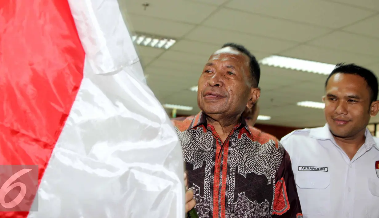 Jannes Johan Karubaba membawa Bendera Indonesia saat akan menjalani sidang, Jakarta, Senin (13/7/2015). Karubaba diduga melakukan korupsi pengadaan "Detailing Engineering Design" di Sungai Mamberamo dan Urumka. (Liputan6.com/Helmi Afandi)