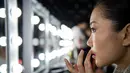 Model merapihkan lipstik dibibirnya sebelum tampil membawakan koleksi Rabbit-Warm karya Zhuang Ganran selama China Fashion Week di Beijing (30/10). (AFP Photo/Nicolas Asfouri)