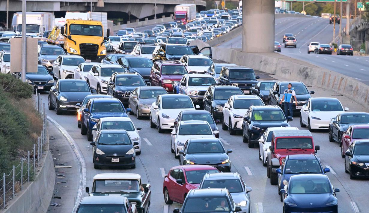 Pada Selasa (28/4/2026), harga minyak Brent yang menjadi patokan internasional, melonjak ditutup di level USD 108,23 per barel. Tampak dalam foto, seorang pengemudi keluar dari kendaraannya (kanan) saat terjebak kepadatan lalu lintas di jalan tol Los Angeles pada 28 April 2026. (Frederic J. BROWN/AFP)