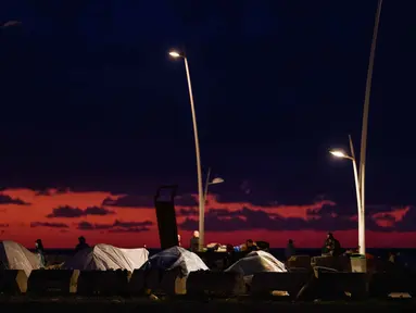 Para pengungsi berjalan di dekat tenda-tenda yang didirikan di sepanjang kawasan tepi laut Beirut, Lebanon, pada Senin 30 Maret 2026. Jumlah pengungsi di Lebanon akibat serangan militer Israel terus meningkat secara signifikan. (Dimitar DILKOFF/AFP)