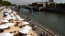 Bantaran Sungai Seine disulap menjadi pantai buatan lengkap dengan pasir dan bangku santai, Perancis, Rabu (22/7/2015).  Tahun ini adalah edisi ke-14 dari Paris Plages, acara budaya dan wisata utama di Paris selama musim panas. (AFP Photo/Miguel Medina)