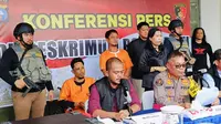 Dua tersangka perampokan bersenjata api (baju oranye) terharap karyawan perusahaan sawit di Kabupaten Kampar. (Liputan6.com/M Syukur)