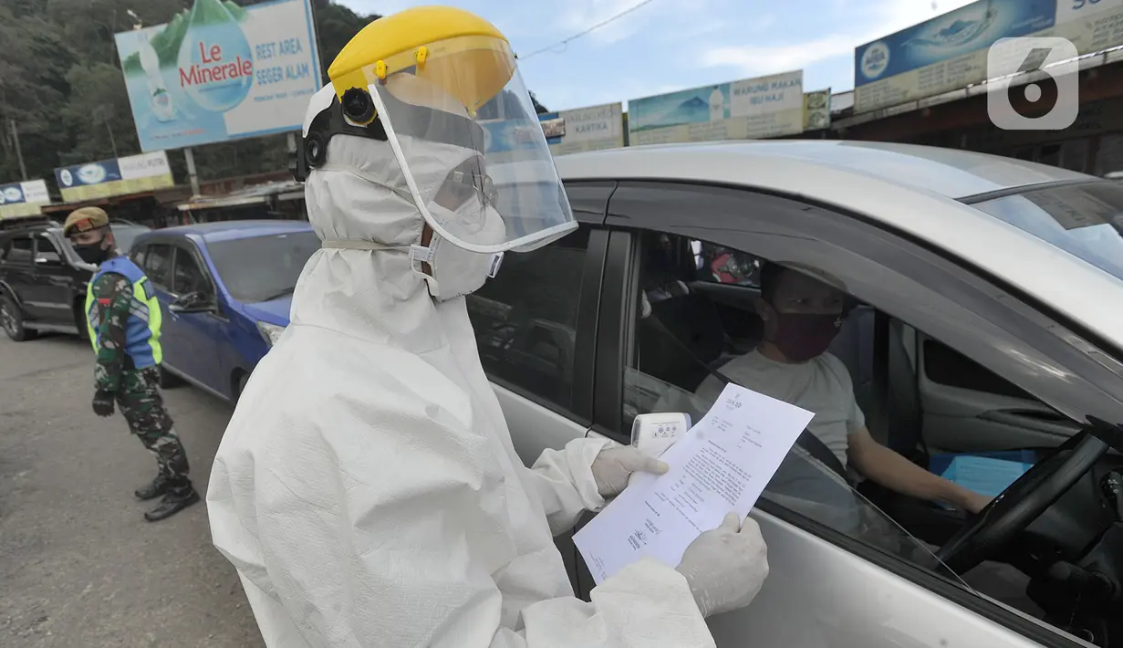 Petugas memeriksa surat keterangan lolos uji rapid test pada warga yang akan melakukan perjalanan di Pos Pam Puncak Pass, Cianjur, Minggu (17/5/2020). Mereka diperbolehkan melakukan perjalanan kecuali dilengkapi surat tugas atau  surat keterangan sehat dari pihak berwenang. (merdeka.com/Arie Basuki)