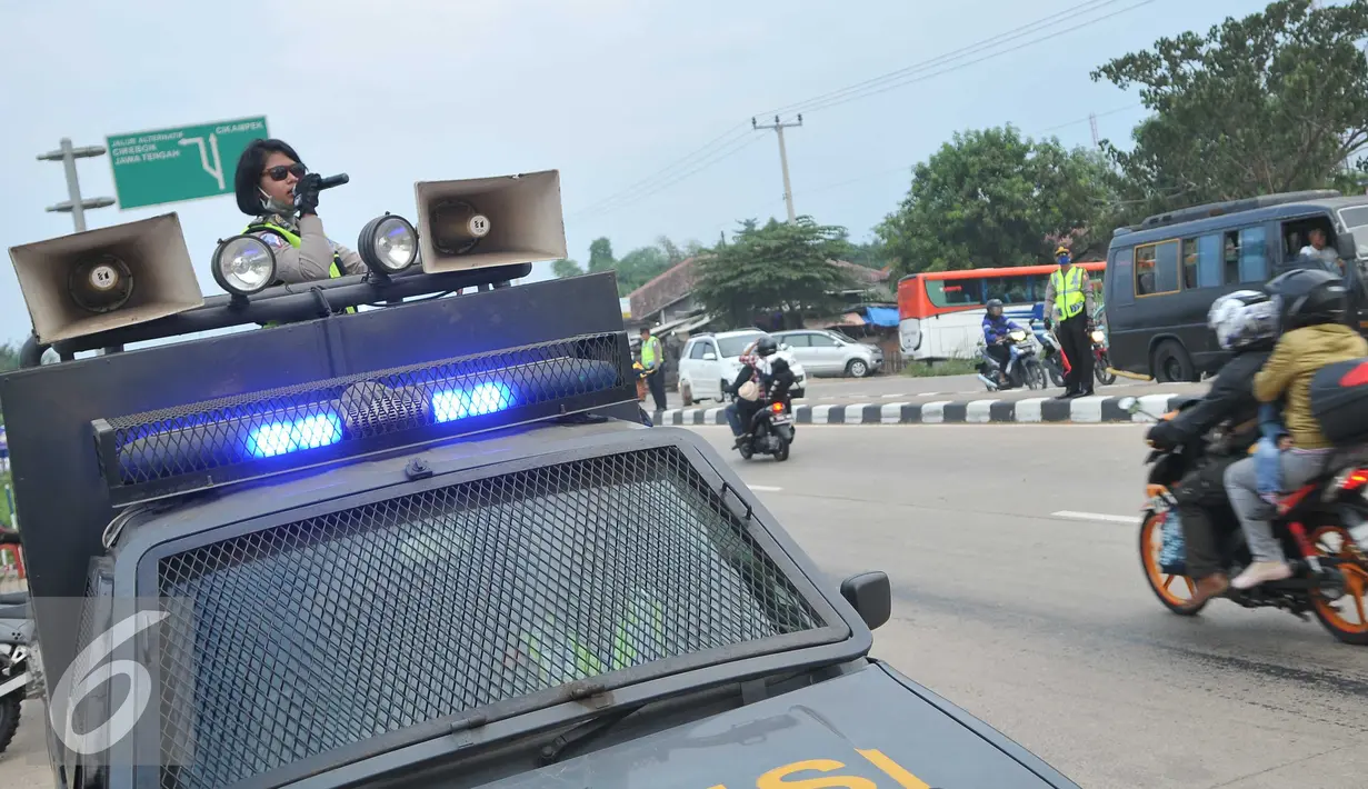 Anggota kepolisian memperingati pengguna kendaraan bermotor untuk mengurangi kecepatan karna pemisah jalan anatara roda dua dan roda empat di jalan Lamaran, Karawang, Jawa Barat, Minggu (3/7).(Liputan6.com/Gempur M Surya)