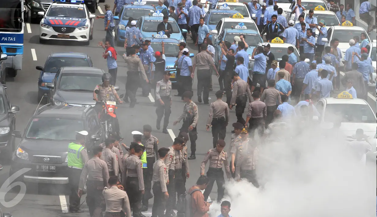 Aparat kepolisian memadamkan aksi bakar ban yang oleh sopir taksi yang melakukan demo di tol dalam kota, Mampang, Jakarta, Selasa (22/3). Tak hanya itu, para sopir taksi juga memblokade jalan sehingga kendaraan tak bisa melintas (Liputan6.com/Johan Tallo)