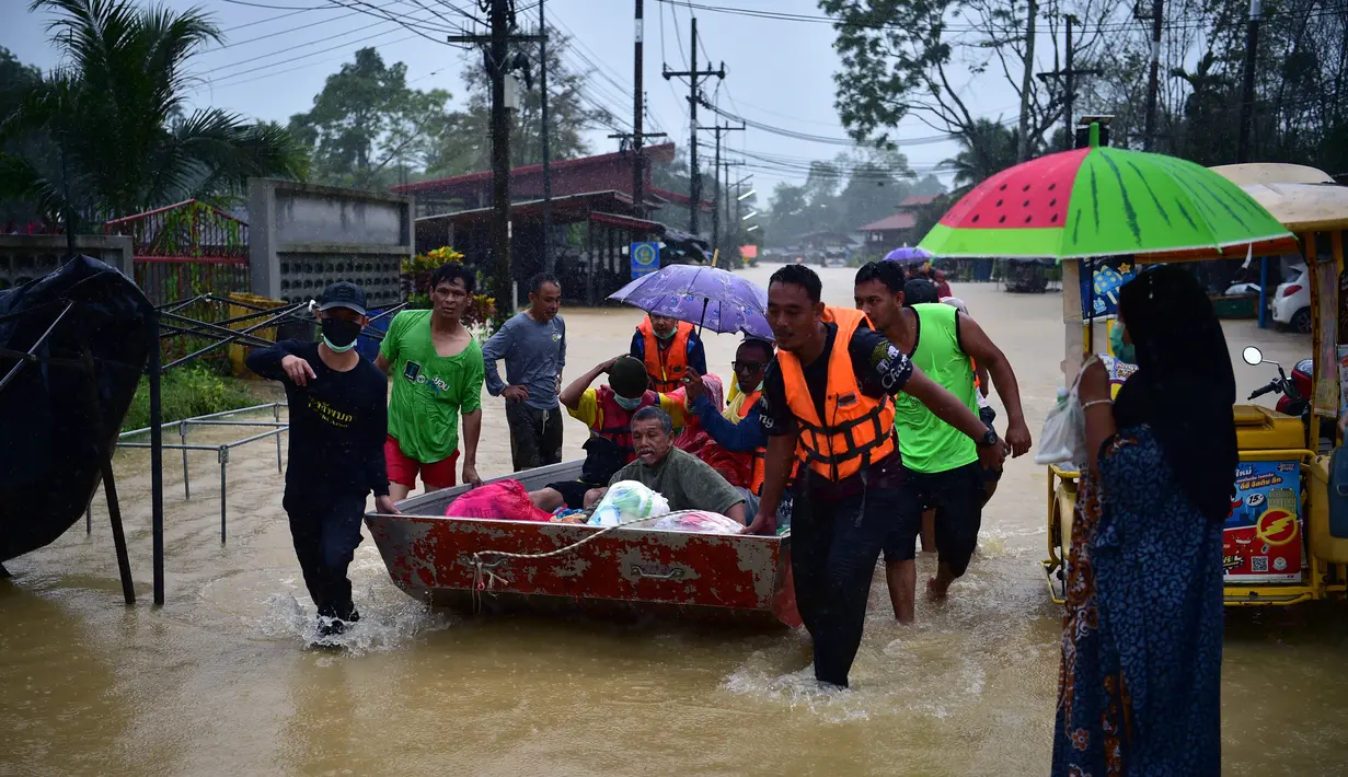 Warga diangkut melalui banjir di distrik Ran-ngea di provinsi Narathiwat, Thailand selatan (26/2/2022).  Lebih dari 7.200 rumah tangga di 195 desa telah terkena dampak, dengan 6.891 rumah rusak, karena Sungai Sungai Kolok yang diguyur hujan terus meluap. (AFP/Madaree Tohlala)
