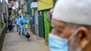Petugas kesehatan tentara berjalan melalui gang saat melakukan vaksinasi virus corona COVID-19 untuk penduduk sebuah wilayah di Kolombo, Sri Lanka, Kamis (12/8/2021). (Ishara S. KODIKARA/AFP)