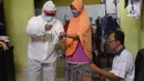 Petugas KPPS dengan mengenakan APD lengkap menandai tinta ke jari warga memberikan hak pilihnya dalam Pilkada Kota Tangerang Selatan di Paku Jaya, Serpong Utara, Rabu (9/12/2020). Mereka mendatangi rumah warga yang tidak bisa mencoblos di TPS karena sakit. (Liputan6.com/Angga Yuniar)