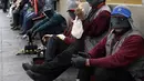 Para tukang semir sepatu bertopeng menunggu pelanggan di kawasan La Paz, Bolivia (29/11). Karena diantara mereka masih ada yang menjalani pendidikan di sekolah dan universitas para tukang semir ini menutup wajahnya. (AFP PHOTO/Aizar Raldes)