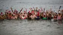 Anggota klub renang "Berliner Seehunde" (Berlin Seals mengenakan topi bertema Natal saat berenang di Danau Orankesee, Berlin yang dingin, Senin (25/12). Berenang di danau itu salah satu tradisi di Berlin menyambut Natal setiap tahun. (AP/Markus Schreiber)