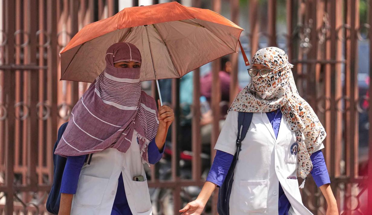 Mahasiswa kedokteran dengan wajah tertutup syal sebagai perlindungan dari terik matahari musim panas, berjalan di Lucknow, India, Rabu 20 Mei 2026. (AP Photo/Rajesh Kumar Singh)
