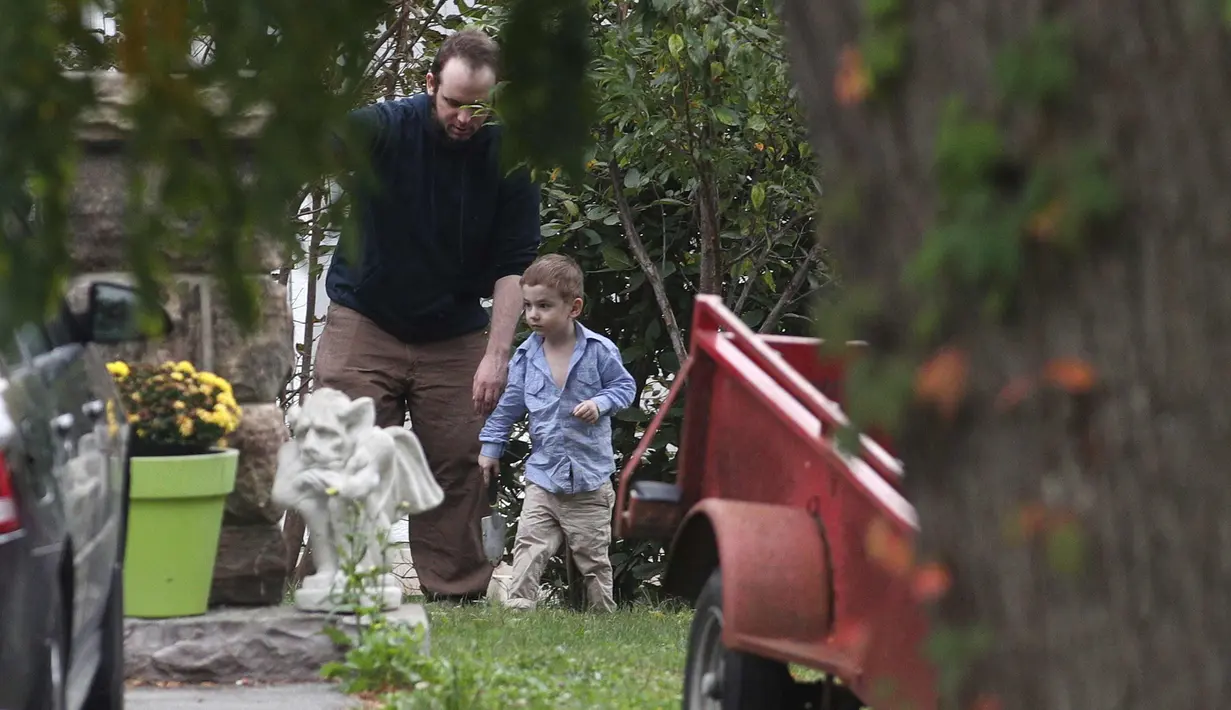 Joshua Boyle bersama anaknya Jonah bermain di kebun di rumah orang tuanya di Smiths Falls, Ontario (14/10). Boyle bersama istri dan ketiga anaknya dibebaskan oleh pasukan Pakistan dari tangan Taliban. (Lars Hagberg/The Canadian Press via AP)