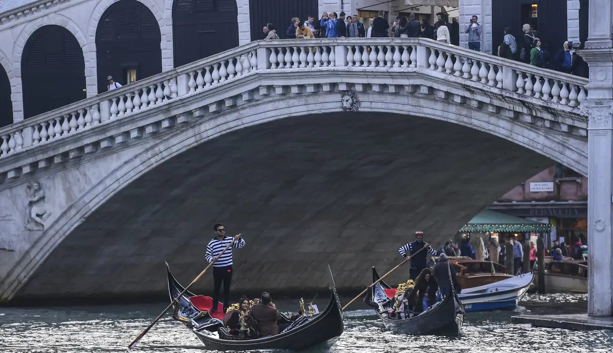 Gondola mengangkut wisatawan di sepanjang Grand Canal di bawah jembatan Rialto di Venesia (4/11/2019). Republik Venesia berdiri di kota ini dari abad ke-9 hingga ke-18. (AFP Photo/Miguel Medina)