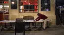 Seorang pramusaji menutup teras bar di Marseille, selatan Prancis, Minggu (27/9/2020). Restoran dan bar di Marseille pada hari Minggu bersiap tutup selama sepekan sebagai bagian dari pembatasan baru baru Covid-19. (AP Photo/Daniel Cole)