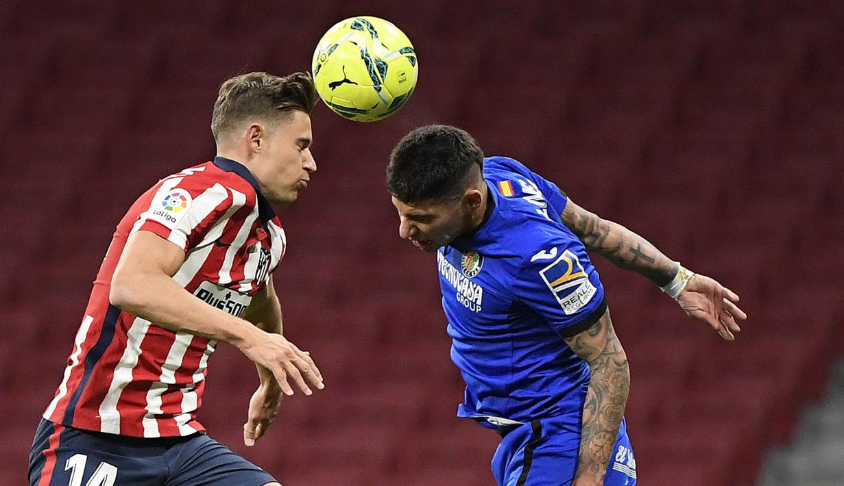 Gelandang Atletico Madrid, Marcos Llorente, duel udara dengan pemain Getafe, Mathias Olivera, pada laga Liga Spanyol di Stadion Wanda Metropolitano, Rabu (30/12/2020). Atletico Madrid menang dengan skor 1-0. (AFP/Oscar Del Pozo)