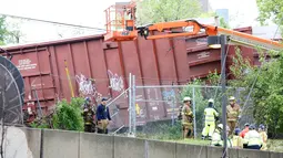 Petugas memeriksa lokasi anjloknya kereta barang CSX hingga keluar dari rel di dekat stasiun kereta komuter Washington, AS, Minggu (1/5). Kereta ini menumpahkan zat kimia berbahaya dan mengganggu lalu lintas kereta api bawah tanah. (Andrew BIRAJ /AFP)