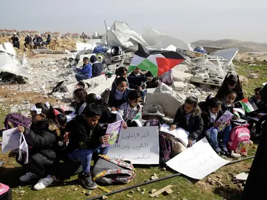 Anak-anak belajar di antara puing-puing sekolah mereka yang hancur di Desa Abu Nuwar, Tepi Barat, Palestina, Minggu (4/2). Hal itu dilakukan setelah tentara Israel menghancurkan sekolah mereka. (AP Photo/Mahmoud Illean)