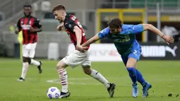 Pemain AC Milan Alexis Saelemaekers (kiri) memperebutkan bola dengan pemain Sassuolo Federico Peluso pada pertandingan Serie A di Stadion San Siro, Milan, Italia, Rabu (21/4/2021). AC Milan kalah 1-2 dari Sassuolo. (AP Photo/Antonio Calanni)