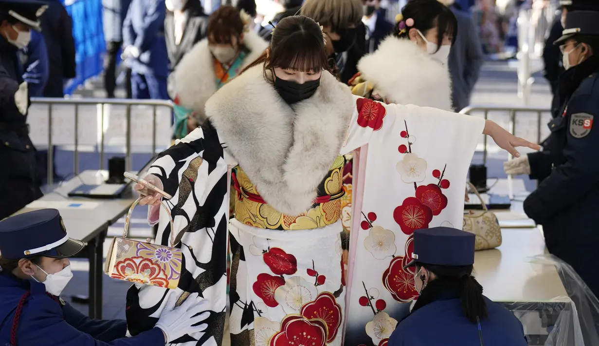 Seorang perempuan Jepang berkimono yang merayakan ulang tahun ke-20, melewati pemeriksaan keamanan untuk berpartisipasi dalam upacara resmi, yang biasa disebut upacara Kedewasaan di Yokohama dekat Tokyo, Senin (9/1/2023). Jepang menurunkan usia dewasa dari 20 tahun menjadi 18 tahun pada 2022. (AP Photo/Eugene Hoshiko)