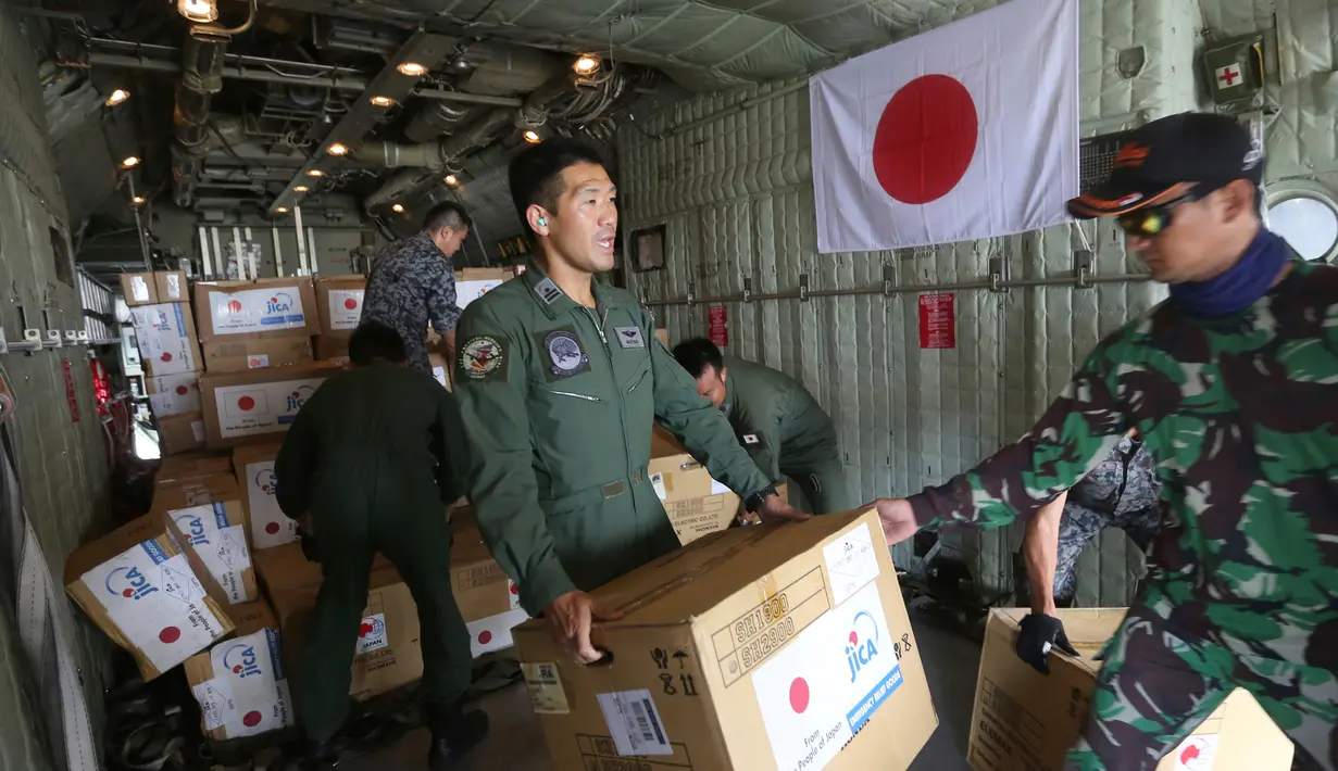 Personil militer Jepang dibantu TNI mengangkut bantuan logistik untuk korban gempa dan tsunami dari sebuah pesawat kargo Angkatan Udara Jepang di bandara Mutiara Sis Al-Jufri di Palu, Sulawesi Tengah, Indonesia (6/10). (AP Photo/Tatan Syuflana)