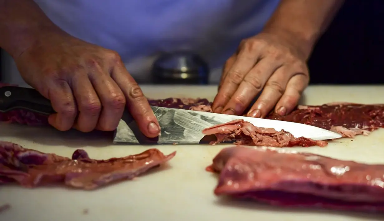 Seorang koki menyiapkan potongan daging untuk dimasak di dapur restoran Don Julio di lingkungan Palermo, Buenos Aires, Argentina, Kamis (20/5/2021). Pemerintah Argentina memutuskan untuk menghentikan ekspor daging sapi selama satu bulan lamanya. (RONALDO SCHEMIDT/AFP)