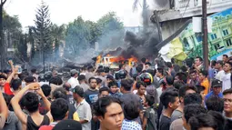 Sejumlah warga berkumpul melihat kecelakaan pesawat Hercules C-130 yang jatuh di kawasan perumahan di Medan, Selasa (30/6/2015). Hercules C-130 milik TNI AU jatuh tidak lama setelah lepas landas. (AFP PHOTO/Muhammad Zulfan Dalimunthe)