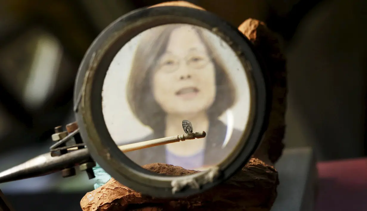 Chen Forng-Sean memperlihatkan karya terbarunya menggunakan kaca pembesar di Taipei, 18 April 2016. Seniman asal Taiwan itu membuat karya lukisan wajah Presiden Taiwan terpilih, Tsai Ing-wen, yang dilukis di atas sebutir beras (REUTERS/Tyrone Siu)