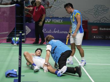 Dokter memeriksa ganda putra Indonesia Yeremia Rambitan yang cedera di dekat rekannya, Pramudya Kusumawardana saat melawan pasangan Malaysia Aaron Chia/Soh Wooi Yik pada perempat final Indonesia Open 2022 di Istora Senayan, Jakarta, Jumat (17/6/2022). Pram/Yere secara dramatis dikalahkan pasangan Malaysia Aaron Chia/Soh Wooi Yik 21-14, 12-21, 20-22. (AP Photo/Dita Alangkara)