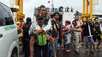Petugas menggendong pengungsi usai turun dari kapal ferry di Pelabuhan Bakauheni, Lampung (26/12). Aktivitas gunung berapi anak Krakatau yang mengakibatkan gelombang tsunami 22 Desember lalu memaksa belasan ribu orang mengungsi. (AFP Photo/Mohd Rasfan)