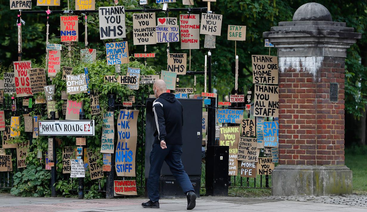 Seorang pria berjalan melewati kumpulan plakat yang dirancang oleh seniman lokal Peter Liversidge untuk mendukung Layanan Kesehatan Nasional (National Health Service/NHS) di London, Inggris, (29/4/2020). (Xinhua/Han Yan)