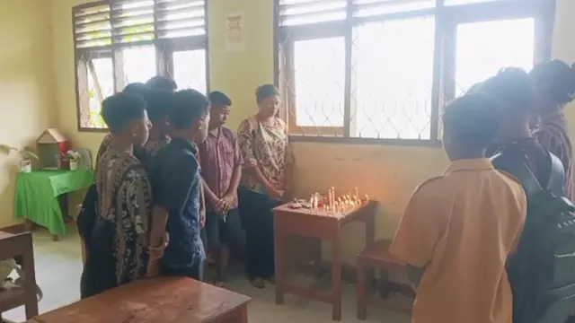 Guru dan teman kelas STN menyalakan lilin di meja ruangan kelas