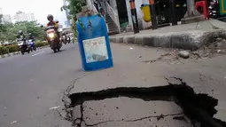 Sebuah rambu darurat diletakkan warga untuk mencegah terjadinya kecelakaan akibat amblasnya sebagian ruas jalan di depan Wisma Bakrie, Jakarta, (12/8/2014). (Liputan6.com/Faizal Fanani)