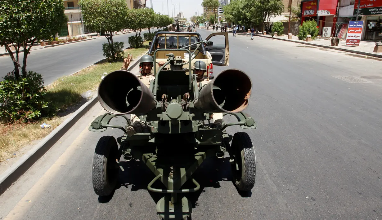 Pasukan keamanan Irak membawa sebuah meriam saat parade militer di Kota Baghdad, Irak, Selasa (12/7). Mulai dari tank, roket, meriam hingga peralatan tempur unggulan lainnya dipamerkan selama parade militer tersebut. (REUTERS/Khalid al Mousily)