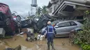 Seorang petugas penyelamat berjalan melewati tumpukan mobil yang hanyut oleh banjir pada puncak Topan Kalmaegi di sebuah permukiman di Kota Cebu, Filipina tengah, pada Selasa 4 November 2025. Sekretaris Jenderal Palang Merah Filipina, Gwendolyn Pang, mengatakan banyak warga terjebak di atap rumah akibat banjir. (Alan TANGCAWAN/AFP)