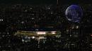 Drone yang membuat formasi menyerupai bola dunia menghiasi langit kota Tokyo saat upacara pembukaan Olimpiade Tokyo 2020, Jumat (23/7/2021). (Foto: AP/Eugene Hoshiko)