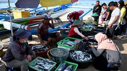 Pedagang melayani pembeli di pasar ikan di Kedonganan, Denpasar, Bali (17/10/2019). Desa Kedonganan terkenal dengan sektor Perikanan, dan juga Pantai Kedonganan yang indah. (AFP Photo/Sonny Tumbelaka)