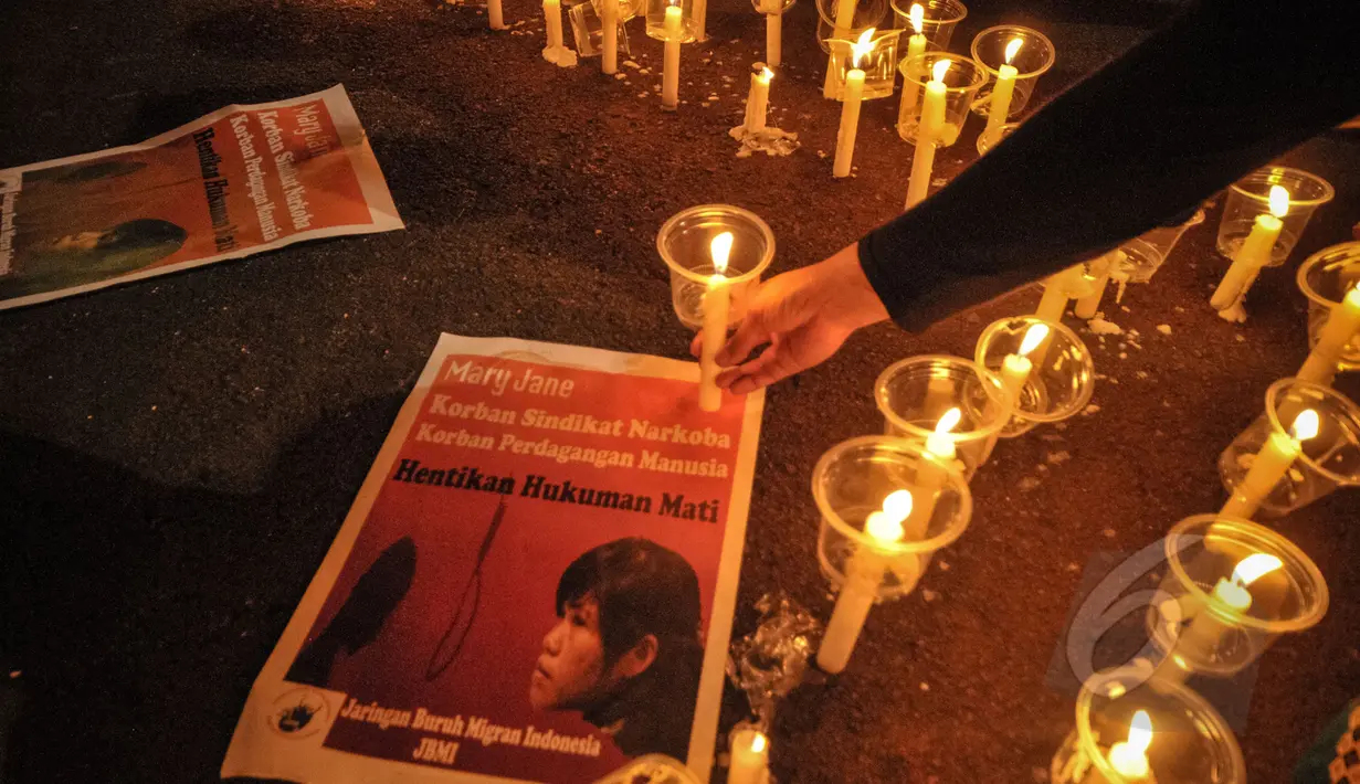 Poster terpidana mati Mary Jane diletakan di dekat lilin saat aksi gabungan komunitas buruh migran di depan Istana Merdeka, Jakarta, Minggu (26/4/2015). Aksi itu menyerukan penolakan atas hukuman mati di Indonesia. (Liputan6.com/Faial Fanani)