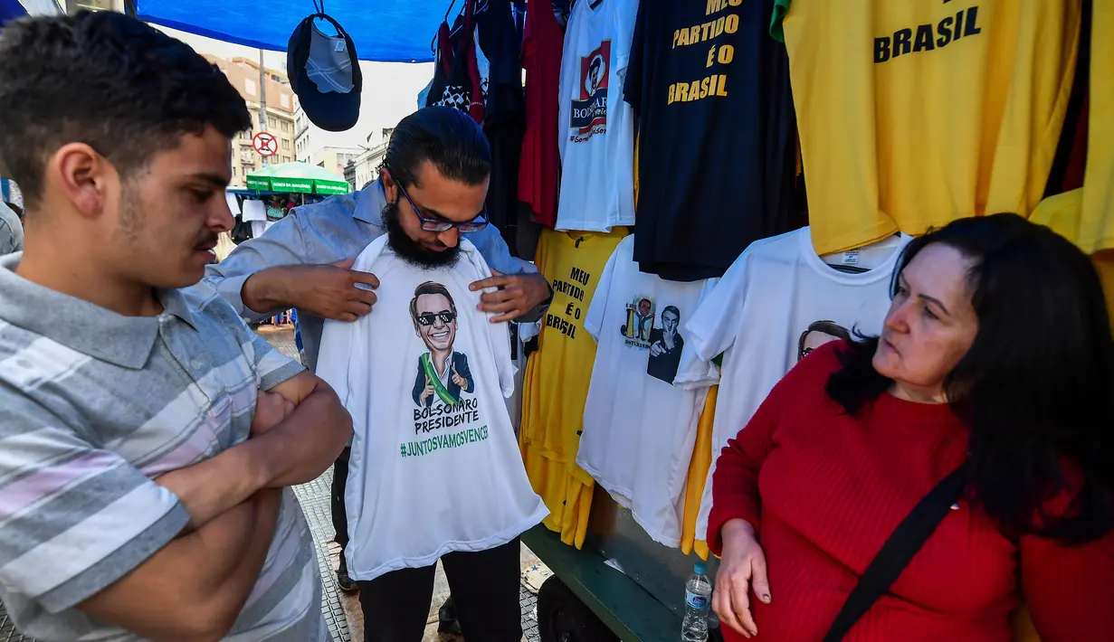 Pembeli memilih kaus bergambar Calon Presiden Brasil, Jair Bolsonaro dari sayap kanan dijajakan di sebuah toko pinggir jalan yang populer di Sao Paulo, 8 Oktober 2018. September lalu, Bolsonaro dirawat setelah ditusuk ketika kampanye. (AFP/NELSON ALMEIDA)