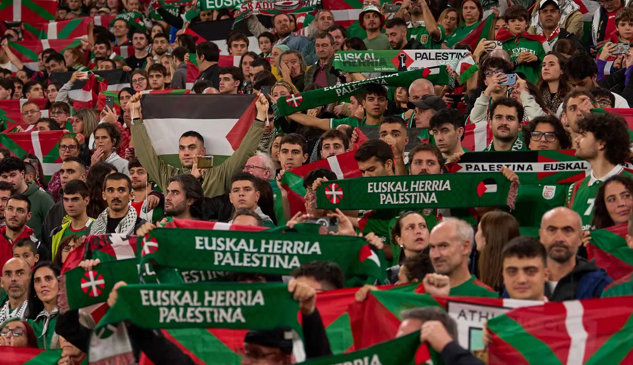 Ribuan penggemar juga berpartisipasi dalam demonstrasi besar di jalan-jalan Bilbao sebelum pertandingan, meneriakkan dukungan untuk Palestina. Tampak dalam foto, para pendukung mengibarkan bendera Palestina dan bendera wilayah Basque Utara selama pertandingan persahabatan antara tim pemain Palestina dan sekelompok pemain Spanyol dari wilayah Basque, yang diadakan sebagai protes terhadap aksi militer Israel di Gaza, di Bilbao, Spanyol, Sabtu 15 November 2025. (AP Photo/Miguel Oses)