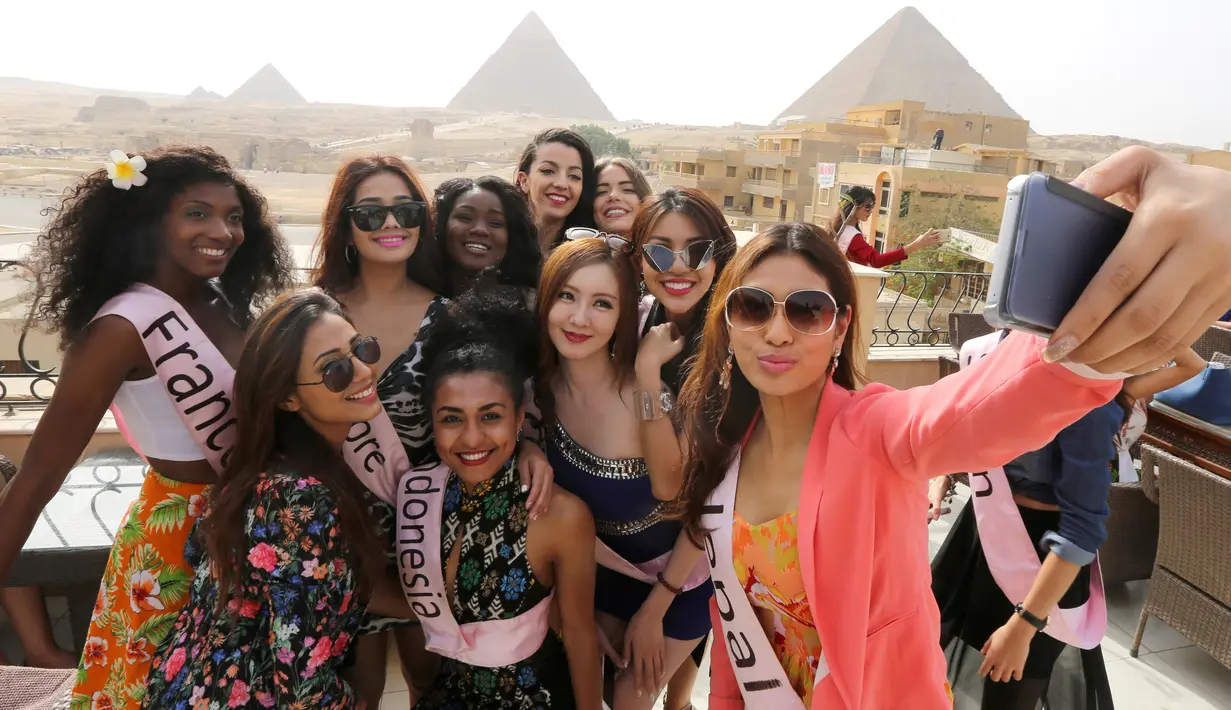 Para Kontestan Miss ECO Universe berselfie dengan latar belakang segitiga piramida di pinggiran Kairo, Mesir (10/4). Pemenang Miss Eco Universe 2016 akan memenangkan hadiah uang tunai USD 10.000. (REUTERS/Mohamed Abd El Ghany)