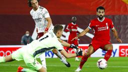 Kiper Arsenal, Bernd Leno, berusaha menghalau tendangan penyerang Liverpool, Mohamed Salah, pada laga Liga Inggris di Stadion Anfield, Senin (28/9/2020). Liverpool menang dengan skor 3-1. (Jason Cairnduff/Pool via AP)