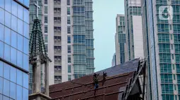 Aktivitas pekerja di atas atap gereja tanpa alat pengaman lengkap, Jakarta, Rabu (12/2/2020). Kemnaker mengatakan tingginya angka kecelakaan kerja di Indonesia disebabkan tidak maksimalnya penerapan K3 yang diatur dalam UU No1 Tahun 1970 tentang Keselamatan Kerja. (Liputan6.com/Faizal Fanani)