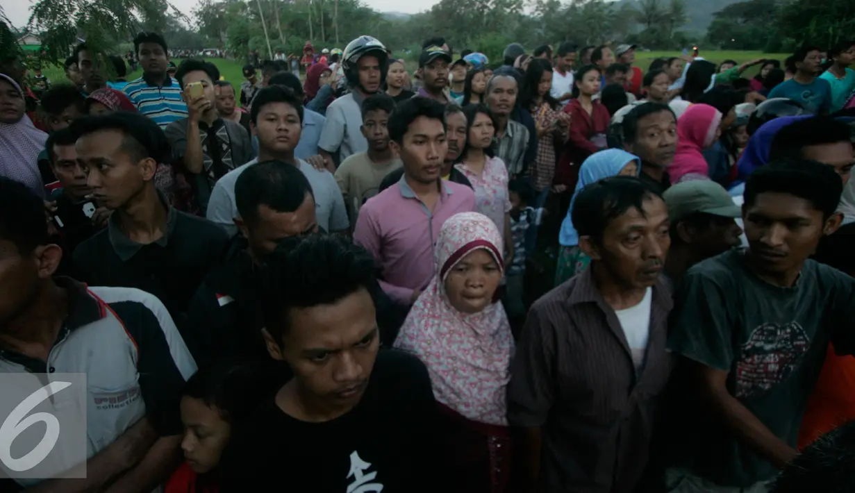 Warga memadati lokasi helikopter jatuh yang sudah di tutup terpal di Dusun Kowang, Sleman (8/7). Heli jatuh setelah melakukan penerbangan dari Solo menuju Yogyakarta. (Liputan6.com/Boy Harjanto)