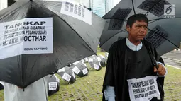 Aktivis dari Gema Tapteng mengenakan payung hitam saat melakukan aksi unjuk rasa di depan gedung KPK, Jakarta, Kamis (26/4). Bakhtiar Ahmad Sibarani dinilai telah memberi suap terhadap mantan  Ketua MK, M Akil Mochtar. (Merdeka.com/Dwi Narwoko)