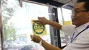 Direktur Utama Perum PPD, Pande Putu Yasa menempel stiker sosialisasi di bus transjakarta saat dilangsungkan tes urine di Pool Bus Perum PPD di Tangerang Selatan, Senin (20/3). (Liputan6.com/Helmi Afandi)