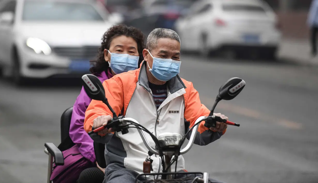 Suami-istri mengenakan masker mengendarai kendaraannya di jalan pada hari yang tercemar polusi udara di Beijing, China (2/4). (AFP Photo/Fred Dufour)