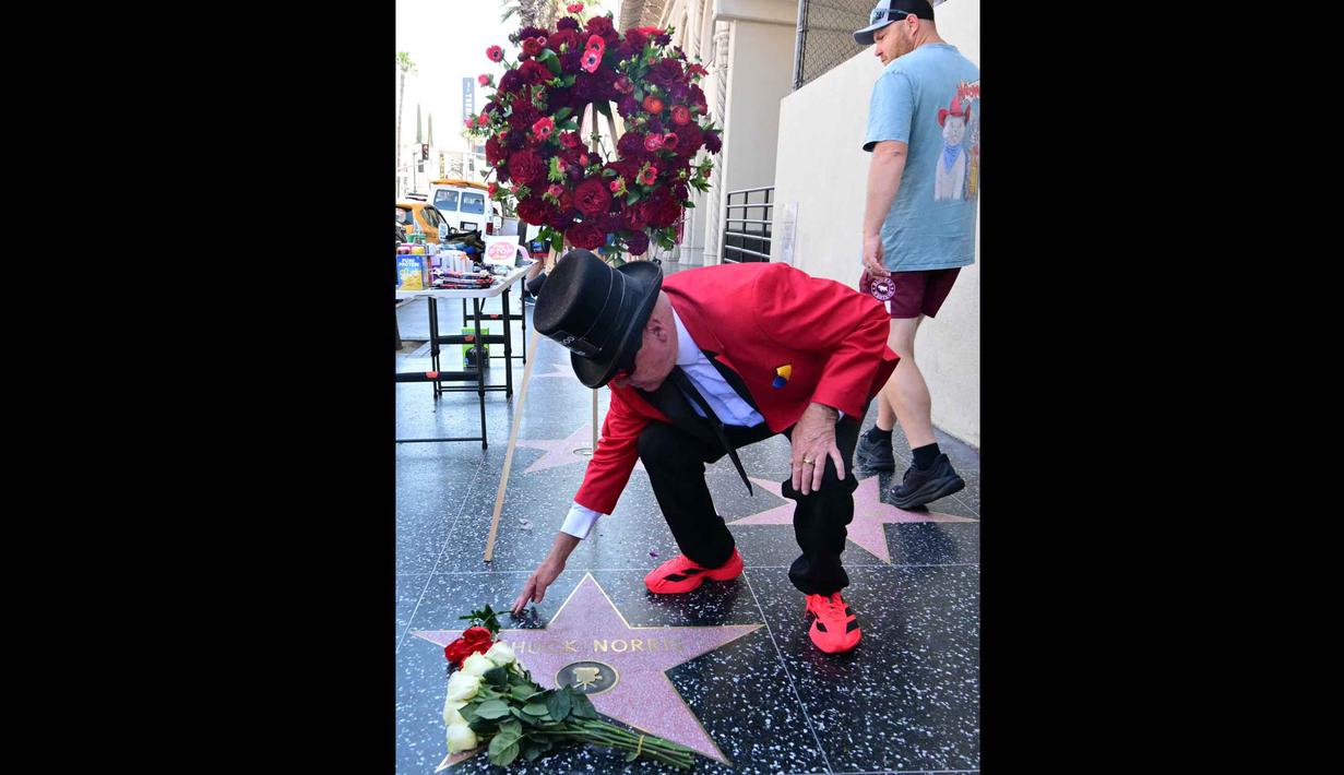 Kabar duka ini disampaikan secara resmi melalui akun media sosial pribadinya pada Jumat (20/3/2026), yang menyatakan rasa kehilangan mendalam atas sosok ikonik tersebut. Tampak dalam foto, warga lokal Dennis Woodruff meletakkan bunga di bintang Hollywood Walk of Fame Chuck Norris, menyusul berita kematiannya pada Jumat 20 Maret 2026, di Hollywood, California. (Frederic J. Brown/AFP)