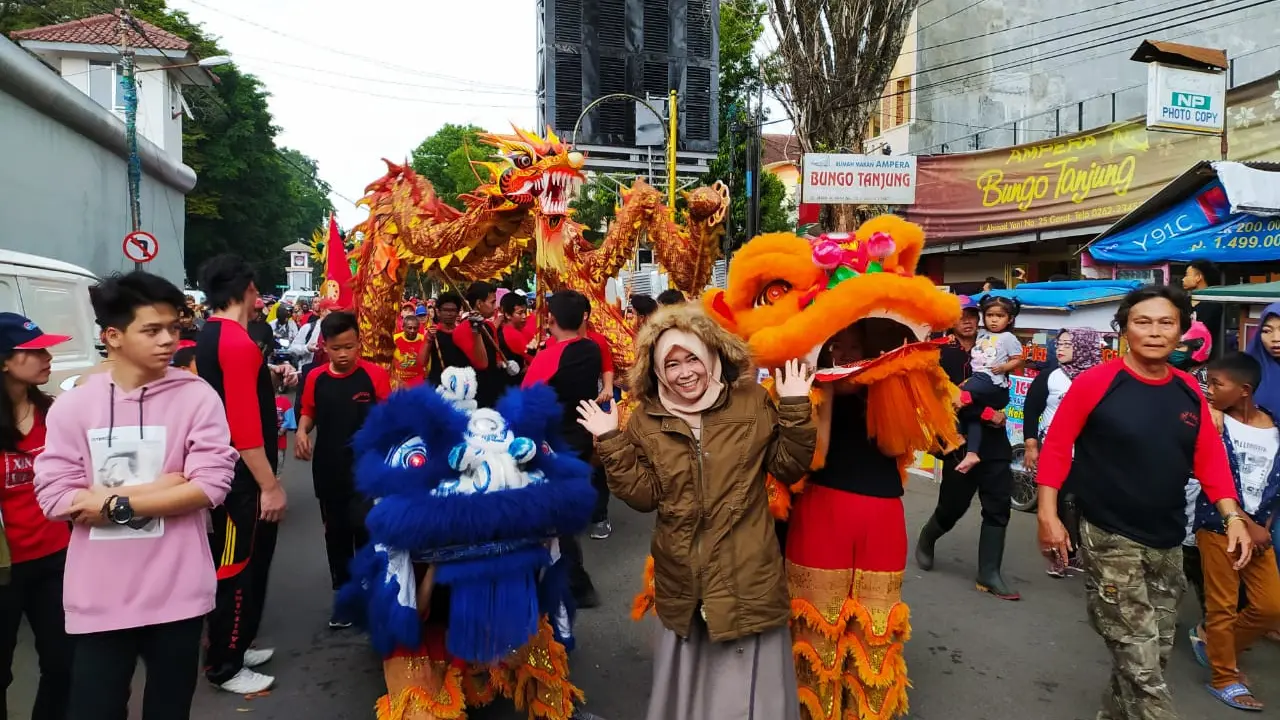 Seorang warga Garut, sengaja berfoto di depan carnaval barongsai dalam puncak perayaan cap go meh di Garut, Jawa Barat