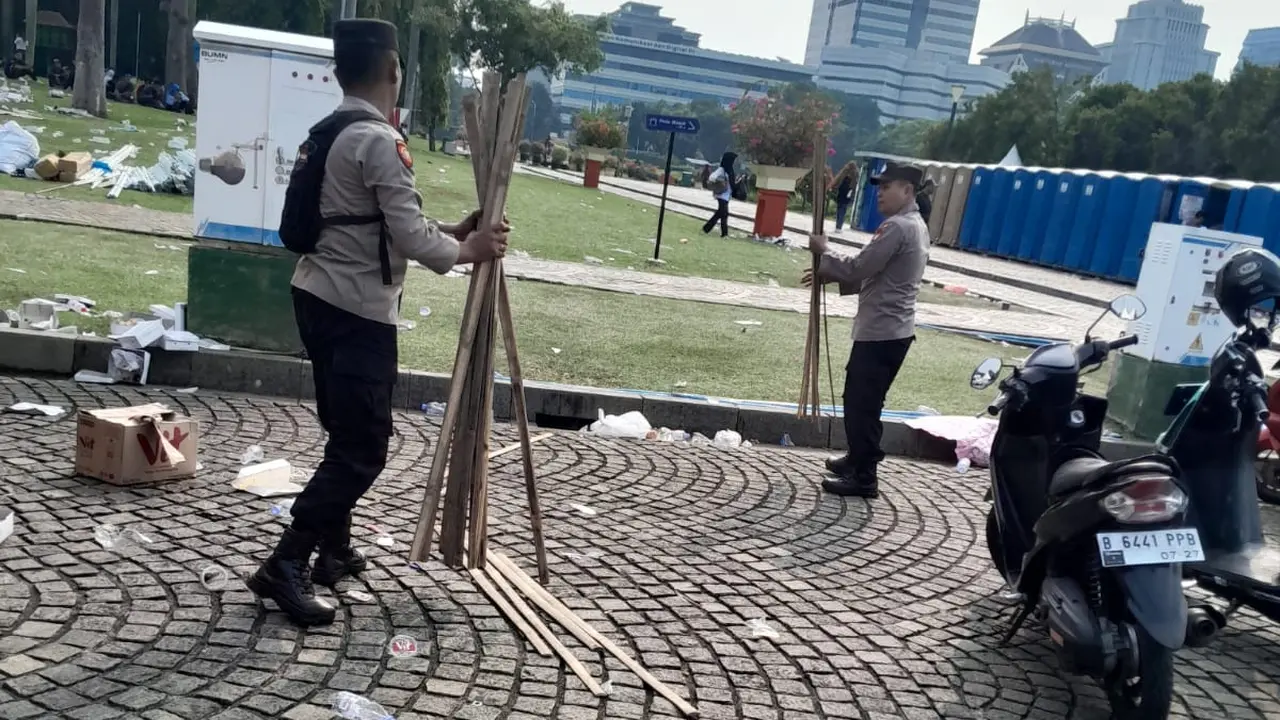 Polri turut membantu membersihkan sisa-sisa sampah usai pelaksanaan May Day di kawasan Monas, Jakarta Pusat, Kamis (1/5/2025) (Liputan6.com/Ady Anugrahadi)